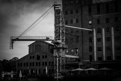 Low angle view of cranes against buildings in city