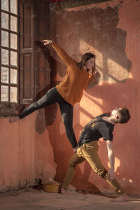 Full length of young woman standing against wall