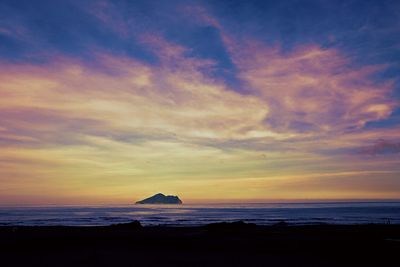 Scenic view of sea against dramatic sky during sunset