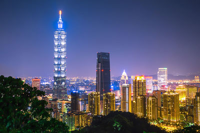 Illuminated modern buildings against sky at night