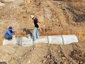 Workers fixing pipe on land