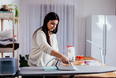 Side view of smiling young woman sitting on table at home