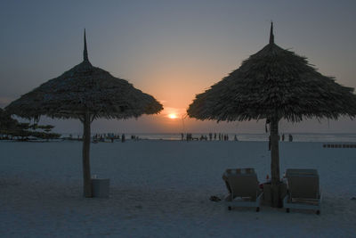 Built structure on beach against sky during sunset