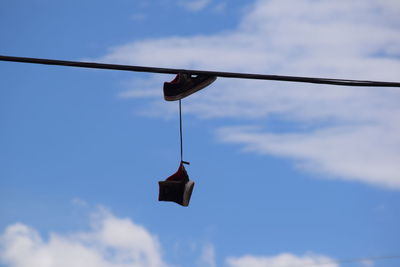 Low angle view of clothespins hanging on rope against sky