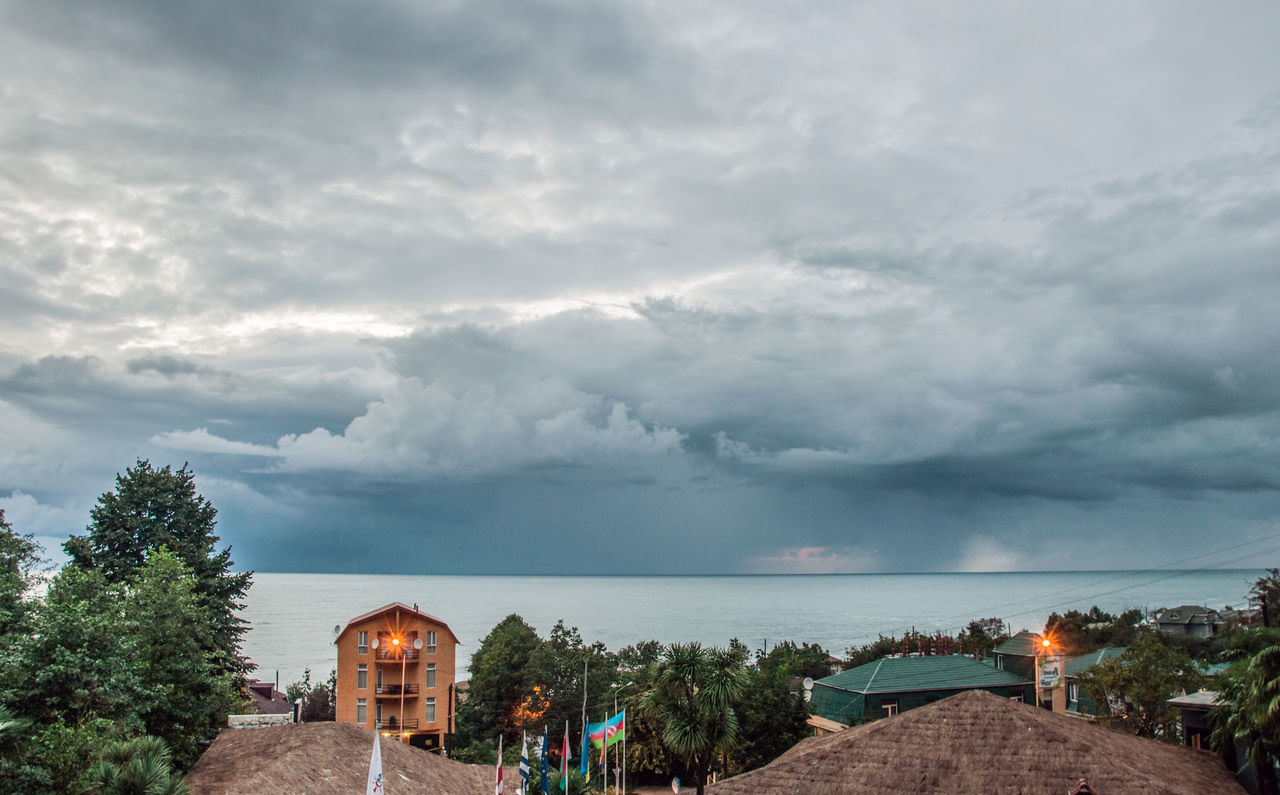 HOUSES BY SEA AGAINST STORM CLOUD SKY