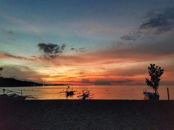 Silhouette people on beach against sky during sunset