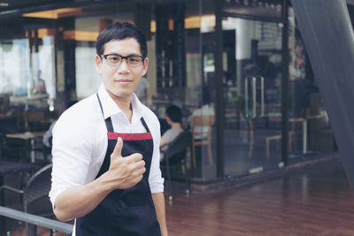 Portrait of waiter showing thumbs up sign at restaurant