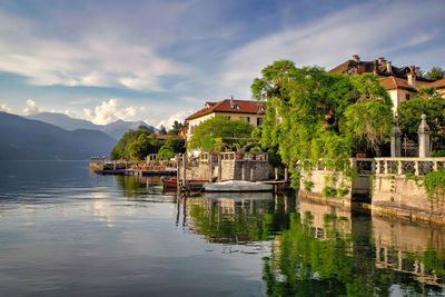 Buildings by lake against sky