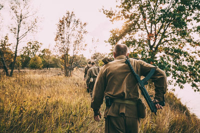 Rear view of men on field against trees