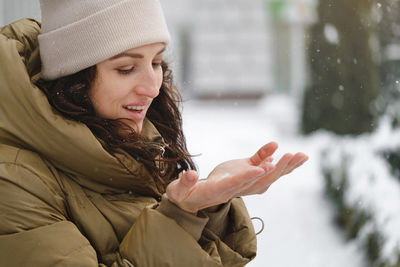 Happy middle age woman catching snowflakes in the city outdoors. relaxed emotional person catching 