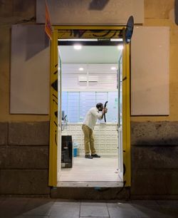 Rear view of man looking at illuminated entrance