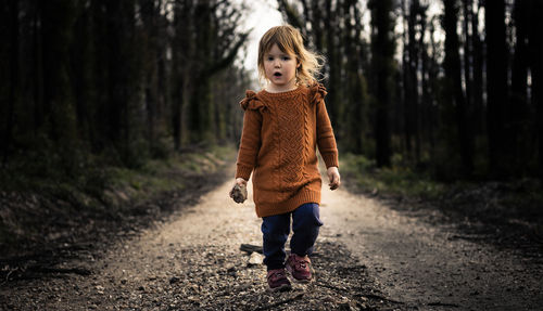 Full length of girl walking on road in forest