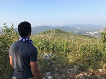 Rear view of teenage boy looking at landscape against sky