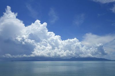 Scenic view of sea against cloudy blue sky on sunny day