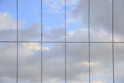 Full frame shot of modern glass building with clouds reflection