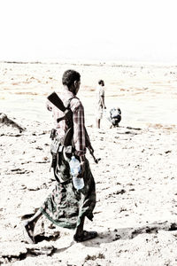 Full length of boy on beach against sky