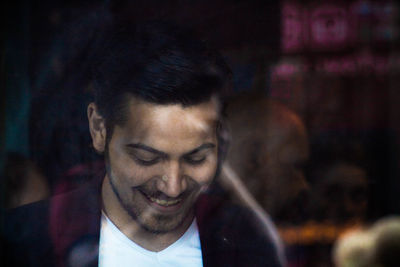 Happy young man in restaurant seen through window