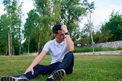 Side view of young man sitting on field