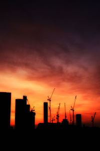 Low angle view of silhouette cranes against sky during sunset