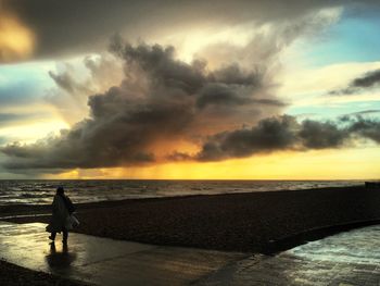 Scenic view of sea against cloudy sky during sunset