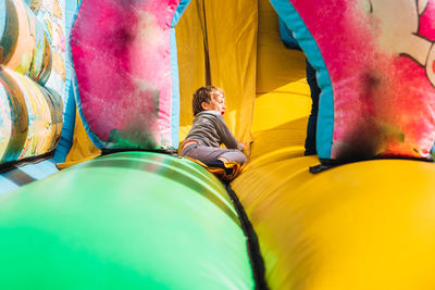 Low section of people sitting on multi colored umbrella