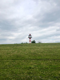 Lighthouse on field against sky