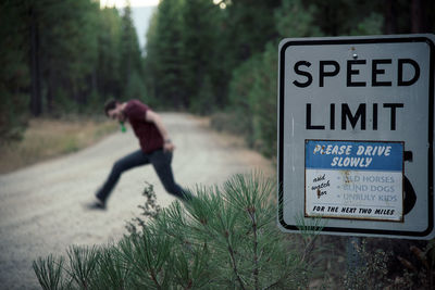 Information sign on road with man in background against trees