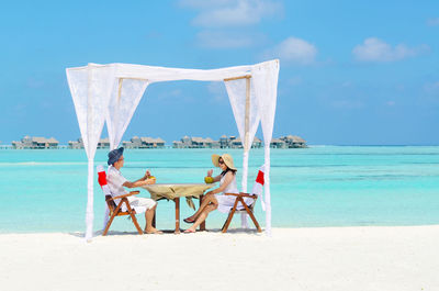 Couple dating at beach against sky