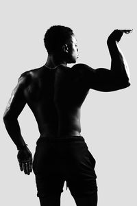 Rear view of shirtless man standing against white background