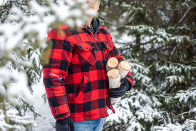 Midsection of person standing by tree during winter