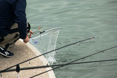 Low section of man fishing in lake