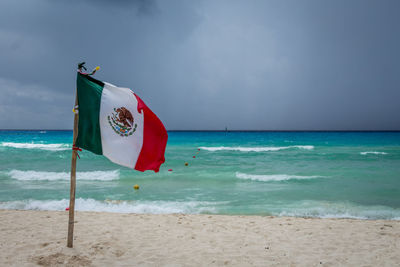 Flag on beach against sky