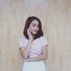 Beautiful young woman standing against wall