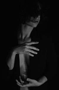 Close-up of woman, tattoo. blazer on black background.