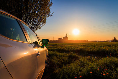 Car on field against sky during sunset