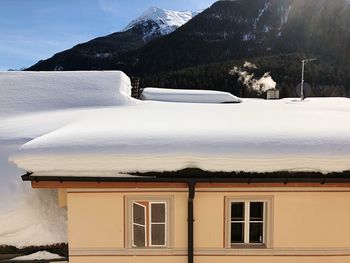 Snow covered house and mountains against sky