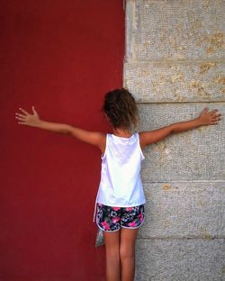 Rear view of girl standing against red wall