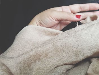 Cropped hand of woman with scarf on black background