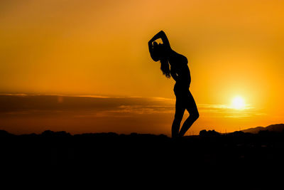 Sensuous silhouette woman against orange sky during sunset