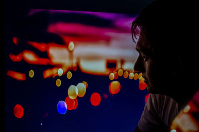 Close-up portrait of boy looking at illuminated lights