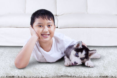 Portrait of smiling boy with dog lying on carpet at home