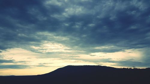 Silhouette landscape against cloudy sky