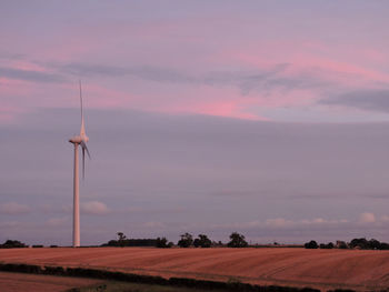 Windmill on field against sky during sunset