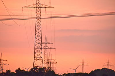 Low angle view of silhouette electricity pylon against sky at sunset