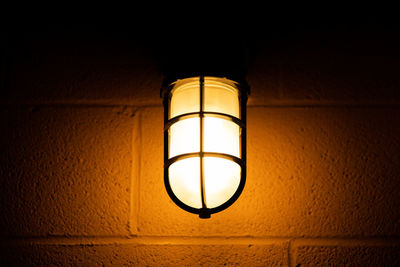 Low angle view of illuminated light bulb hanging on wall