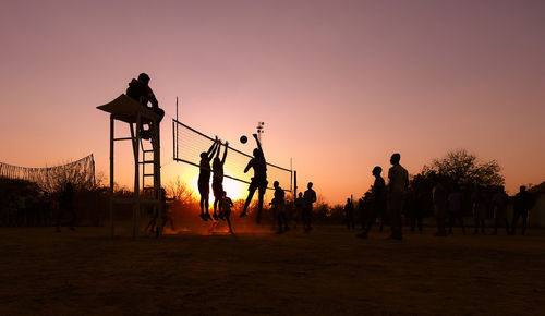 Silhouette people on field against clear sky during sunset