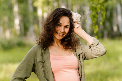 Portrait of young woman standing against trees