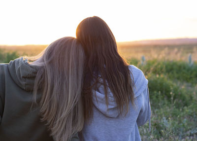 Two girls back to back watching the sunset person