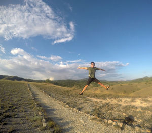 Full length of excited man jumping on landscape against sky