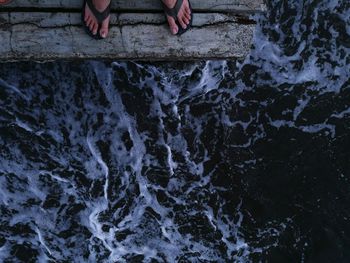 Low section of woman standing on pier over rippled sea